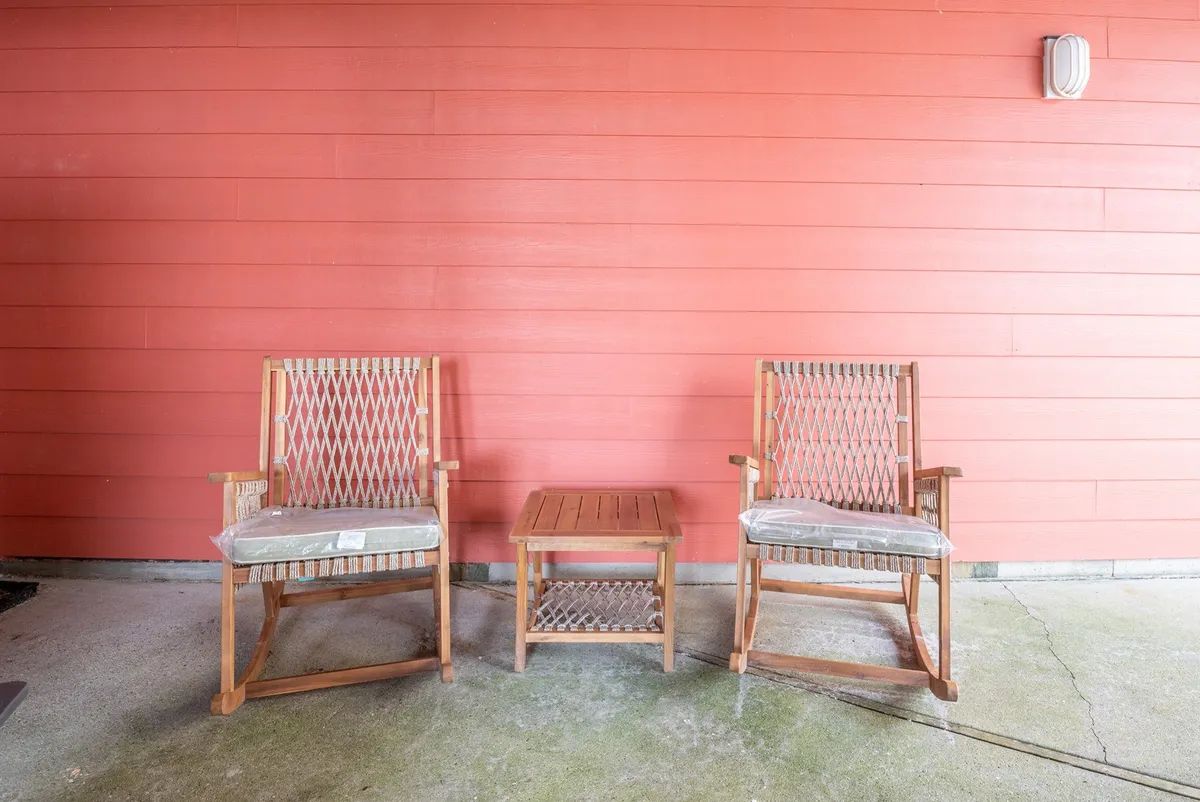 Two inviting rocking chairs and a small wooden table set on a deck, facing out toward open space. The relaxed setup suggests a place to unwind and take in the natural surroundings after a day of adventure.